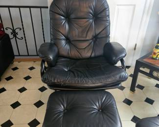 One of a pair of black leather stressless chairs with ottomans