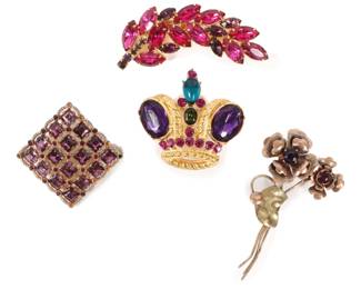 Lot 222
Rhinestone jewelry 4pc. group: Trifari gold tone crown brooch, 1/20 10K gold filled flower bouquet brooch, Art Deco square purple rhinestone brooch, and feather/leaf brooch with pink rhinestones.