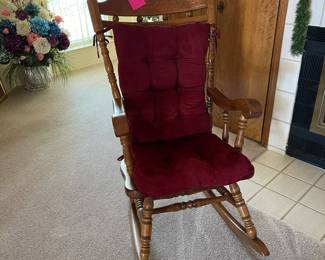 Large oak rocker with burgundy cushion.