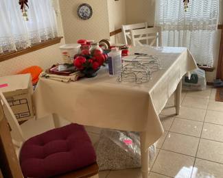 Farm table with white legs and blonde wood top. Four chairs.