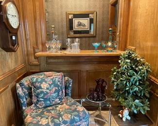 Vintage upholstered chair, faux plant, wall clock, vintage amethyst blown glass pitcher with glasses, mid-century chrome and glass accent table