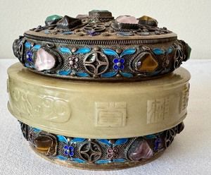 Antique Chinese Precious Stone Inlaid Cylinder Box with Jade Bracelet 

Beautiful cylindrical box covered with silver filagree and inlaid with cabochons of tiger's eye, jadeite, pink quartz and amethyst. Features a carved middle ring with Chinese characters. Measures about 4" x 2.5"

Circa 1900-1940