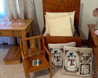 Antique child’s potty chair, antique wooden chest, decorative pillows