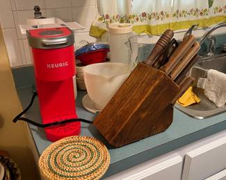 Keurig machine, butcher block with knives, trivets, and other miscellaneous kitchen items.