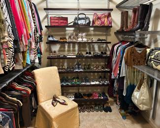 Lovely walk in closet filled with women’s clothing, shoes, boots, handbags 