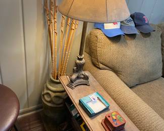 Side table and lamp hiding pottery vase filled with poison spears.