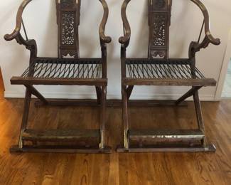 Chinese Horseshoe Back Folding Hunting Chairs with Leather seat straps, brass accents and carved wood.