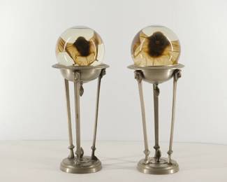 A pair of metal pedestals, each with a crystal ball containing a preserved bat