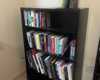 A smaller bookshelf full of large coffee table books