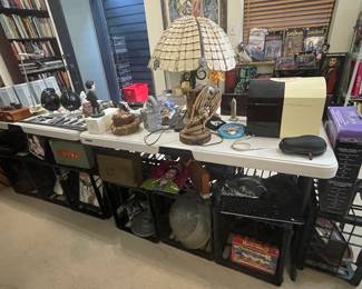 Display table full of assorted home goods and decor including a dragon table lamp with a glass/mica shade