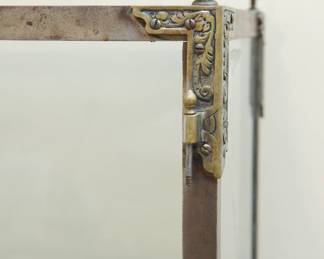 Top corner finial detail of cast iron and glass vitrine or display case with decorative finials and two sculptural dragons at the top center with two glass doors