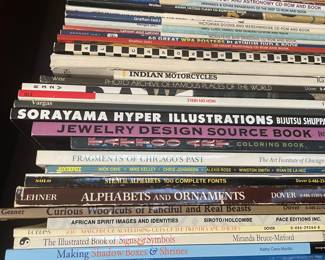 Book collection including: "Al Capones Hideaways", "Indian Motorcycles", "Photo Archive of Famous Places of the World", "High on Heels", "Vargas", "Sorayama Hyper Illustrations", "Jewelry Design Sourcebook", "Tattoo Art Coloring Book", "Fragments of Chicago's Past", "Juxtapose Magazine", "Stencil Alphabets: 100 Complete Fonts", "Alphabets and Ornaments", "Curious Woodcuts of Fanciful and Real Beasts", "African Spirit Image and Identities", "930 Matchbook Advertising Cuts of the Twenties and Thirties", "The Illustrated Book or Signs & Symbols", and "The Making of Shadow Boxes and Shrines"