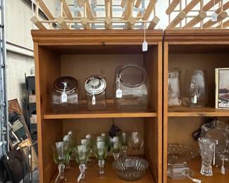 Vaseline glass and glass serving pieces in two pine shelves, many wine racks