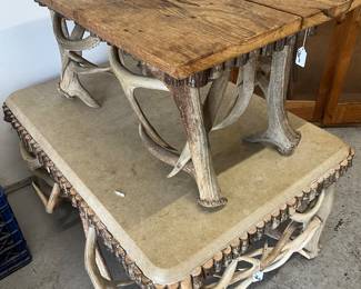 Two tables one with a concrete top deer antlers and cedar the other is rustic wood and deer antler
