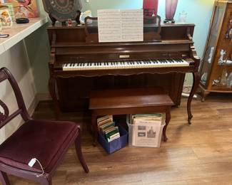 Baldwin piano with stool, music and music books and a chiar coverd in velvet with musical back