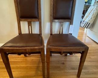 Pair of leather and wood chairs with bronze inlay at the top.