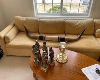 L shaped soft yellow couch, horns, coffee table