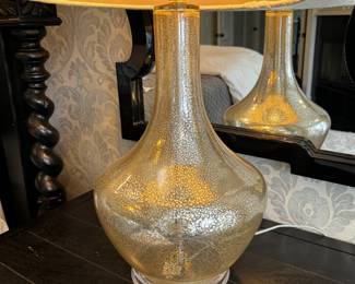 11) $100 - Set of two glass lamps with white shades. Lamp base is 12" x 12" and shade measures 15". 32" in height. One lamp is missing a piece of the finial.