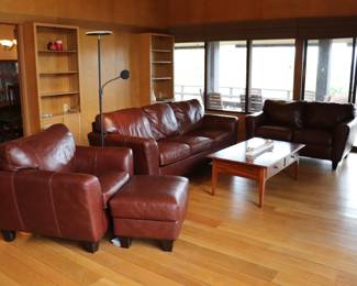 Set of reddish brown leather sofa, love seat, and arm chair with ottoman