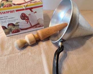 Aluminum colander cone sieve strainer with 11 inch vintage wooden pestle masher and an apple peeler.