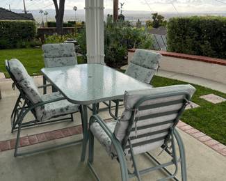 Here is a nice outdoor patio set: a rectangular glass-top table and four matching chairs.