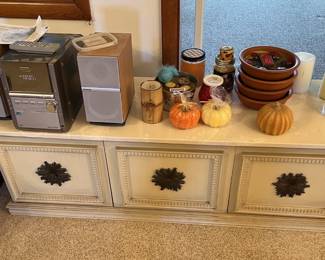 This picture shows a small bookcase stereo, a few pumpkin decorative items, bowls, and candles.