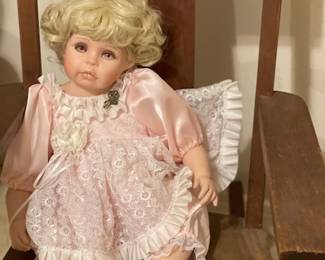 One of many dolls in a collection, a small rocker, and a couple of small chairs too