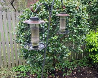 Double bird feeders on hanging poles.