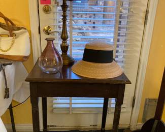 side table with glass vase, hat, and lamp
