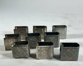 (9PC) SILVER PLATE NAPKIN RINGS | Silver plate napkin rings in the shape of books decorated with floral and geometric patterns with space on spine for a name or initials.