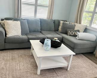 White coffee table and sectional couch. The couch has a tear on one side so it is just looking for a good home!