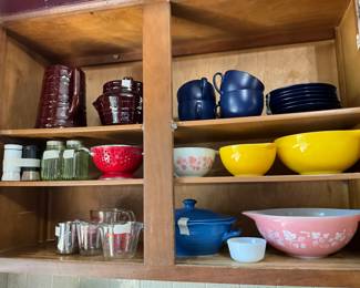 Kitchen - Pyrex bowls, measuring utensils, red small strainer, dishes with cups, Marquest pitcher, bowl & canister on left top shelf 