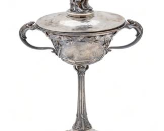 Signed 'E. Sichel' Art Nouveau Silver Plate Covered Tazza, Ca. 1920, H 12" W 6" L 8" | with a nude playing an aulos on the cover handle. the bowl has lizard form handles with Art Nouveau floral and tendril motifs throughout the bowl, stem, and base. Signed 'E. SICHEL' to the base. Circa 1920. Provenance: Property from a prominent Grosse Pointe Park, MI private residence. 