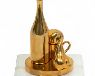 Paul Suttman (American, 1933-93) Bronze Sculpture, Ca. 1970, "Midas Feast", H 6.5" Dia. 4" | Signed at the base. Bronze still life of a wine bottle, coffee mug, apple and pear. Label on the underside reads "J. Walter Thompson Co. commission Buon Natale 1973 135/300". Having an acrylic display case. Provenance: Property of Prominent Collector, Birmingham, Michigan
