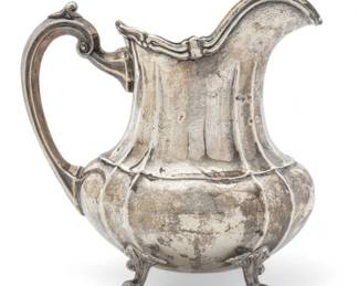 Fisher Silversmiths (American) 'Duncan-Footed Duncan' Sterling Silver Water Pitcher, H 9.25" W 5.5" L 9" 27.39t oz | the pitcher offers scrolling forms and ribbed motifs to the bodice. Terminating on four scrolling lobed feet. Bearing signature branding and hallmarks to the underside. Total weight: 27.39 troy ounces. Provenance: Property from a private collection, West Bloomfield Township, Michigan.