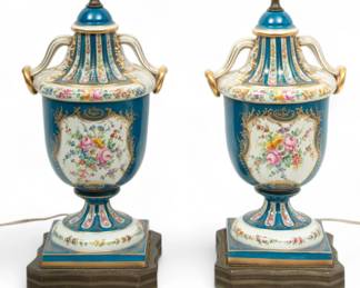 French Sevres Style Painted Porcelain Urns, Converted to Lamps, Ca. 1930, H 33" W 8.5" L 10" 1 Pair | Made in France. the painted porcelain urns offer sprays of flowers and berries throughout accented with a bleu celeste ground and fired gold trim. with scrolling arms on the shoulders with affixed gold fired rings. Shades included, measuring H 14.25" X W 14" X L 20" individually. Electrified lamps. Provenance: Property from a private collection, West Bloomfield Township, Michigan.
