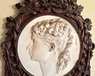 Relief medallion bust of a woman. Signed. In hand carved wood frame.