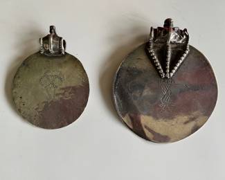 A pair of Omani silver Samt pendants with text from the Quran on the front and a shackled jinn on the reverse—these were worn to ward off bad luck