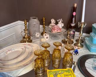 Brass candlestick holders, amber color depression glass goblets, china platters