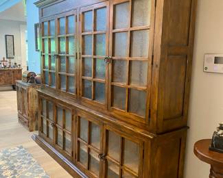 2 piece wood and glass  wall unit, L -8 ft 7” x 7 ft 7” tall, x 1 ft 7” deep. The top section is 54” tall and the bottom section is 36” tall.  Note: The family has set a reserve pricing on this piece