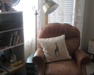 Leather chair, giraffe accent pillow, floor lamp, books