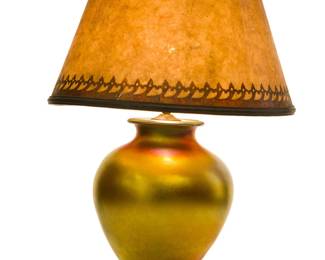 3115
20th Century
An Iridescent Gold Art Glass Table Lamp
Appears unmarked
The likely Steuben gold Aurene-style vase-form standard issuing two lights and raised on a carved wooden base set with a period mica shade
25.75" H x 11.5" Dia.
Estimate: $200 - $300