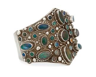 241
A Carmen Beckmann Mexican Silver And Opal Cuff Bracelet
Carmen Beckmann (b. 20th century)
Circa 1960-1980; San Miguel de Allende, Mexico
Stamped: Bekmann / Mexico / Sterling
A chunky sterling silver hinged cuff with multiple bezel-set fire opal cabochons, with silver balls and rope wire accents
6.5" inner C x 2.625" H
134.8 grams gross
Estimate: $800 - $1,200