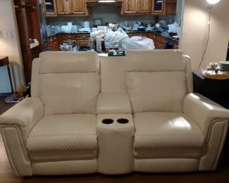 White leather power reclining loveseat with cup holders. Includes battery power attachment.