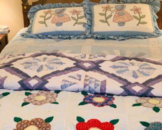 queen bed with several quilts