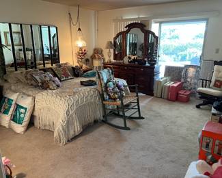 This particular picture shows a number of items including a bed, dresser, rocking chair, pillows, and a mirrored headboard.