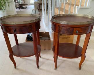A set of matching bedside or coffee tables with burled wood and metal tray tops.