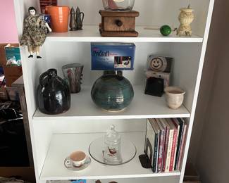 Ceramics, crocks, cookbooks and more all displayed on a five shelf bookcase.