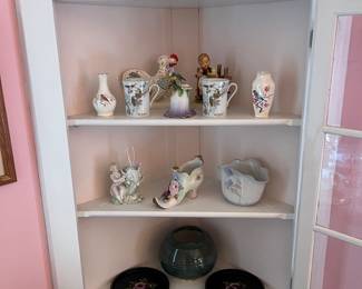 Ceramic figurines and black lacquer plates displayed on corner hutch.