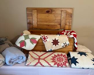 Early quilts and wooden blanket chest.